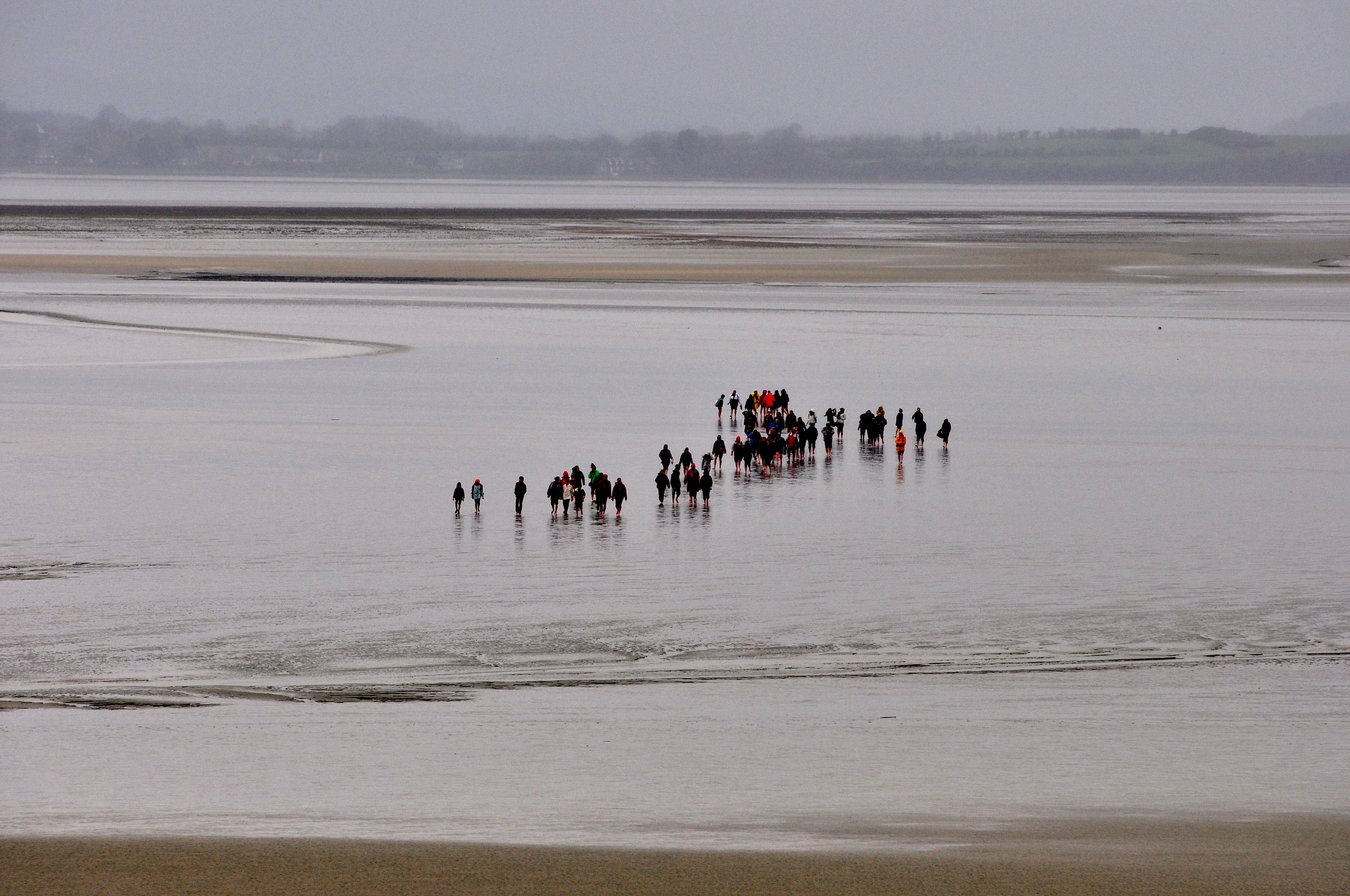Os turistas fazem a travessia dos peregrinos no frio intenso da primavera da Normandia.