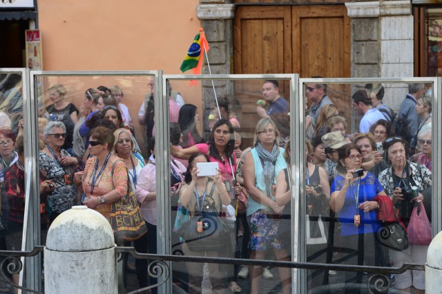 Os turistas observam a fonte através do vidro.