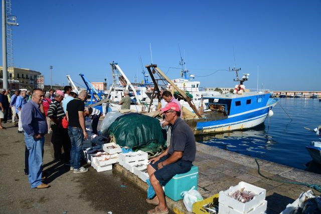 Pescadores vendem o peixe do dia no cais do porto.