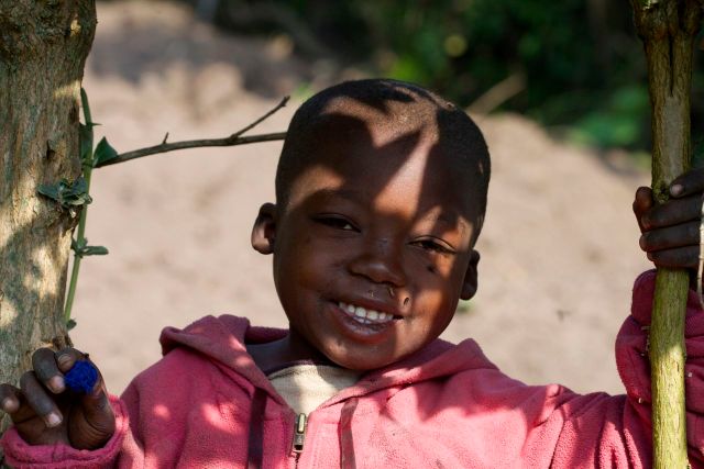 Criança na beira da estrada observando os carros de safari.