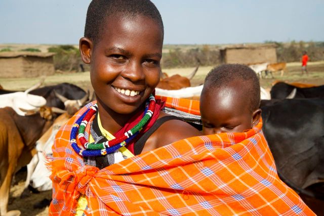 Jovem mulher Masai com o filho nas costas.